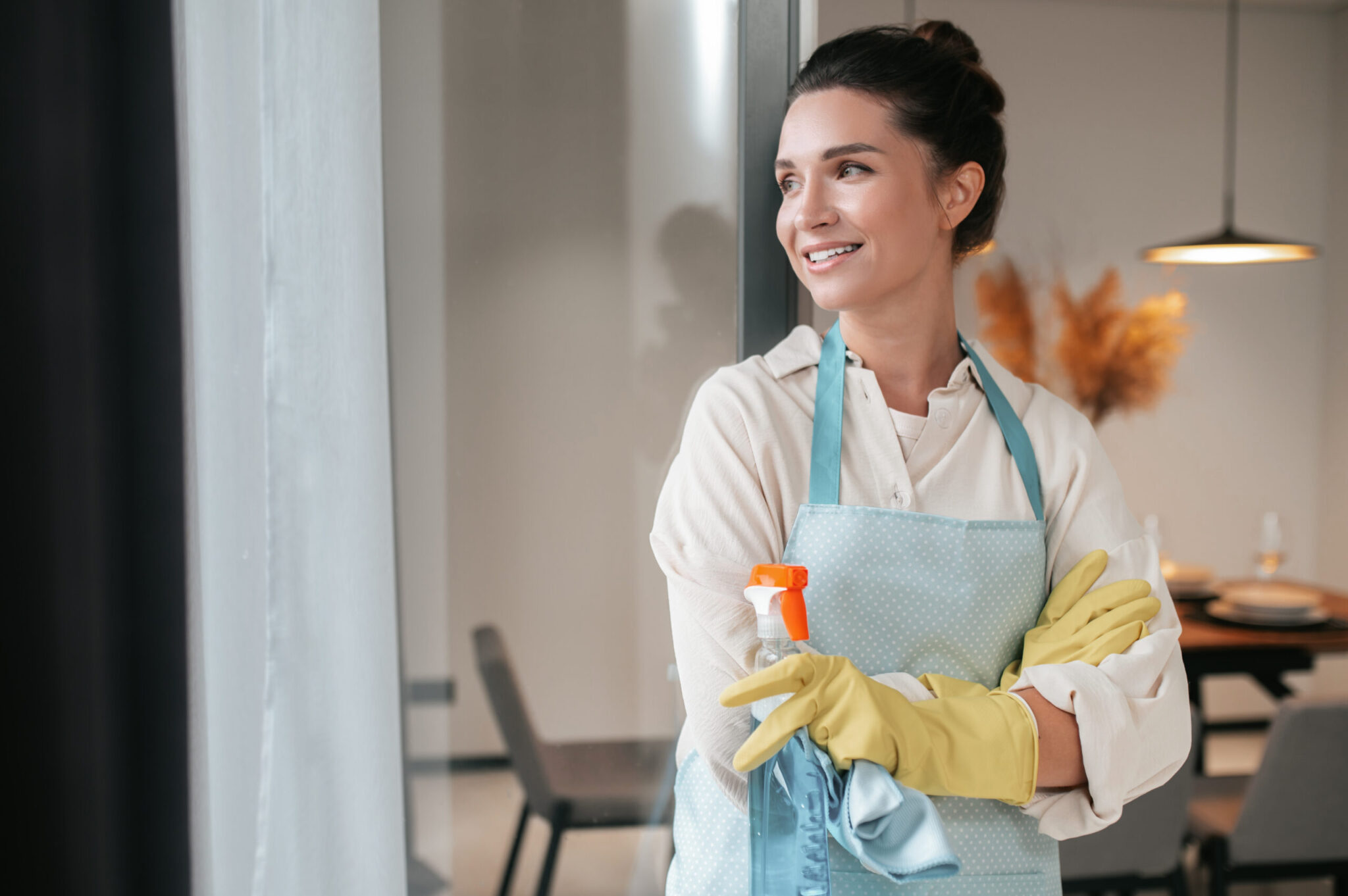smiling housewife in apron standing in the kitchen