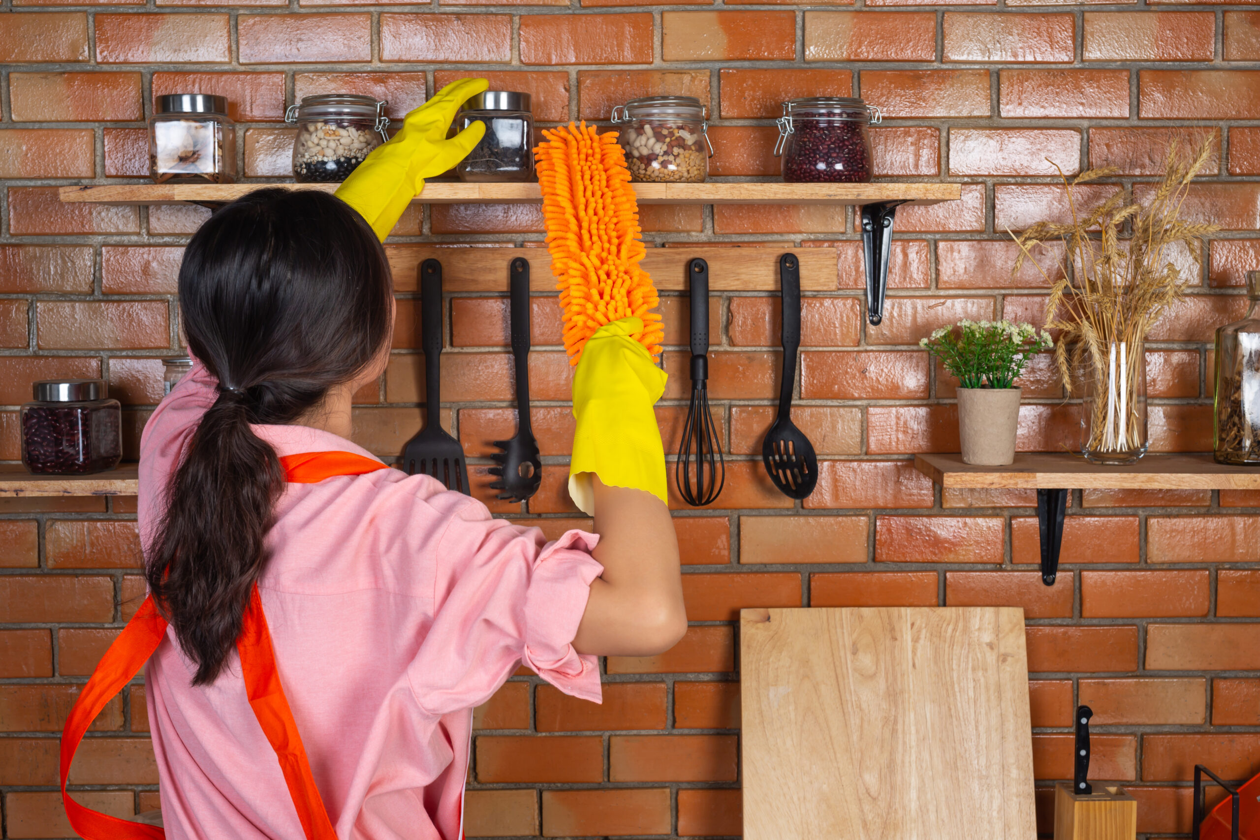 young girl is wearing yellow gloves while cleaning the kichen ro